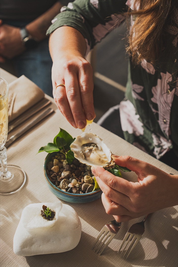 A guest squeezing lemon over an oyster at the table during the From Seas, Lakes and Oceans event at Przystań & Marina