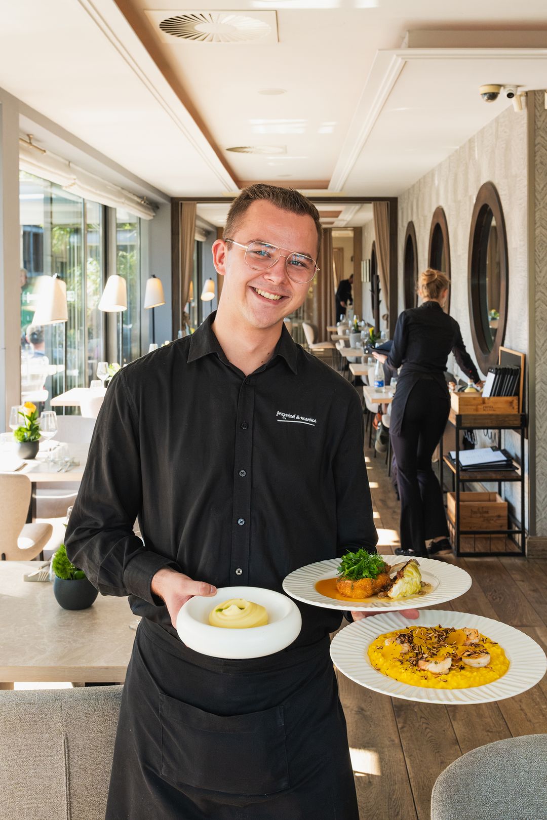Front-of-house team member at Przystań & Marina serving dishes from the menu